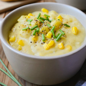 Hearty vegan potato corn chowder in a bowl topped with pepper and green onions